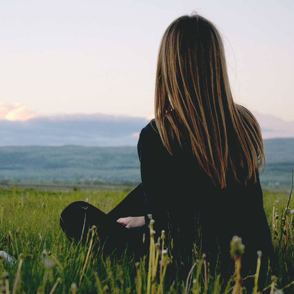 Woman reflecting and sitting in a field
