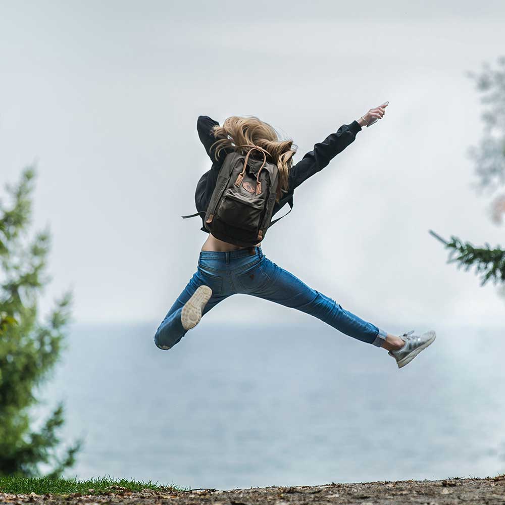 woman jumping in the air on a trail