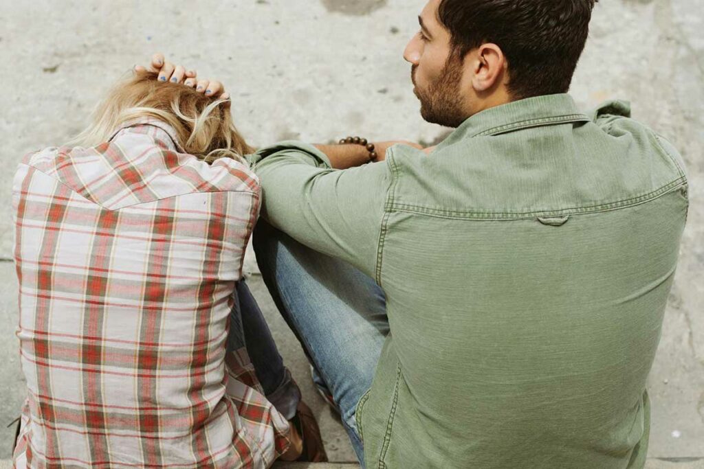 Man and woman sitting on steps discussing their relationship